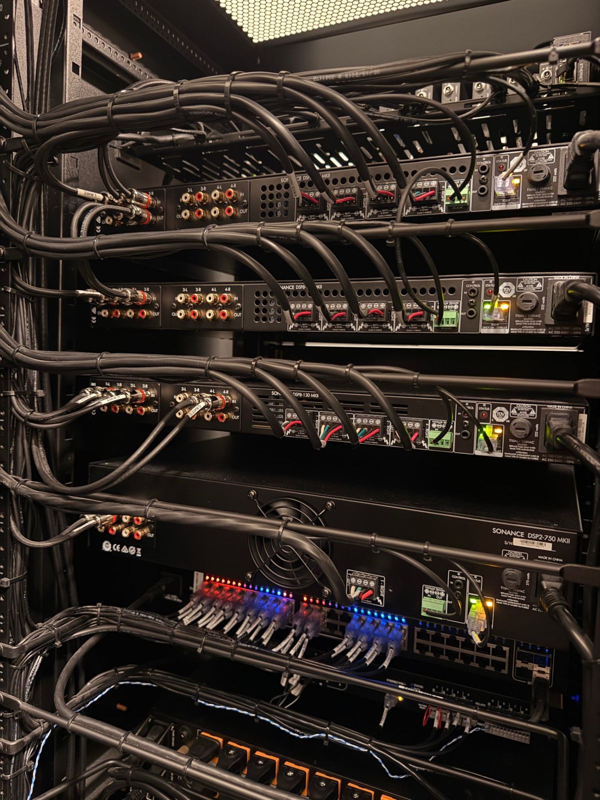 The back of a rack of Sonance multi-zone amplifiers with every speaker run labeled and dressed